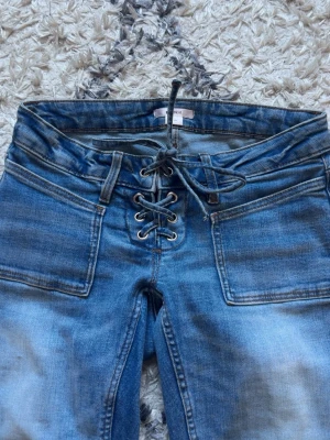 Blå bootcut jeans med snörning - Säljer de super trendiga och väldigt eftertraktade jeansen från Gina med snörning i midjan! ❣️☺️ Storlek 14+ S. Långa på mig som är 160 cm.  