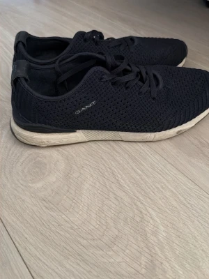 Svarta sneakers från Gant - Snygga svarta sneakers från Gant med stickad ovandel i mesh för extra andningsförmåga. Skorna har klassisk snörning och vit sula med svarta detaljer. Perfekta för en sportig och avslappnad stil.