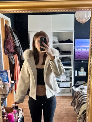 Beige kappa med fuskpälsluva från Gina  - Populär beige pälsjacka med stor fluffig luva från Gina. Passar perfekt nu till våren. Användt den 1 gång, inprincip ny, säljer då den inte kommer till användning 