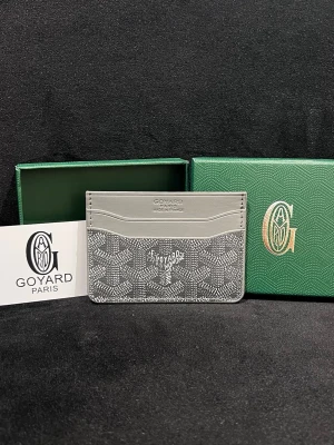 Grå kortfodral från Goy4rd - Snyggt grått kortfodral från Goy4rd med klassiskt mönster och vit logotyp framtill. Tillverkat i canvas och läder med flera kortfack. Perfekt för dig som vill ha en stilren och exklusiv accessoar från Paris.