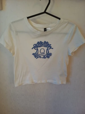 Vit croppad t-shirt med blått tryck - Vit croppad topp med blått tryck framtill