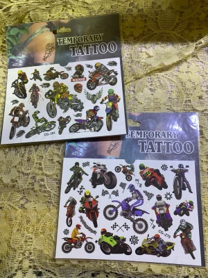 Fyrpack temporära tatueringar - Säljer fyra ark med temporära tatueringar. Två ark har coola motorcyklar och förare i färgglada nyanser, medan de andra två har söta djurmotiv i glada färger som lejon, hundar och katter. Perfekt för att piffa upp stilen med roliga och unika detaljer.  50kr/2st/bild 