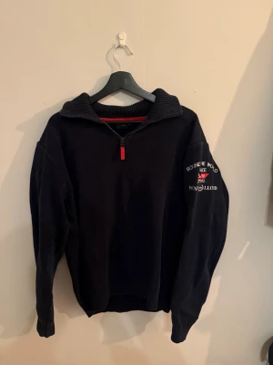 Henri Lloyd stickad tröja – mörkblå – strl L-XL - Stilren stickad tröja från Henri Lloyd i mörkblå nyans. Modellen har en halv dragkedja vid kragen och diskreta detaljer som ger ett sportigt men samtidigt sofistikerat uttryck.  Plagget är i gott skick med normalt bruksslitage.  Storlek: L-XL Passform: Normal Färg: Mörkblå Skick: 8/10  📦 Kan skickas 💬 Kontakta vid frågor eller intresse