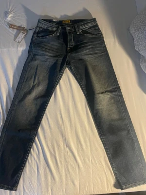 Mörkblå (tapered mike)jeans från Jack & Jones - Snygga mörkblå tapered mike jeans från Jack & Jones med klassisk femficksdesign och subtila slitningar. Jeansen har normal midja och raka ben, tillverkade i stretchigt denim för extra komfort. Perfekta för en trendig och avslappnad stil. Storlek 32/34 och kostar 499kr. Helt oanvända!! Säljer för att jag inte diggar de.  Köpta för 550kr från Jack and Jones. 