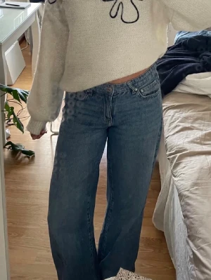 Blå wide jeans - Säljer ett par blåa jeans med låg midja och breda ben. Jeansen har klassisk femficksdesign, dragkedja och knapp framtill. Perfekta för dig som gillar en avslappnad och trendig look. Materialet är jeans i bomull. Använda sparsamt i ca 3 månader! Uppsydda men går att lägga ner igen!