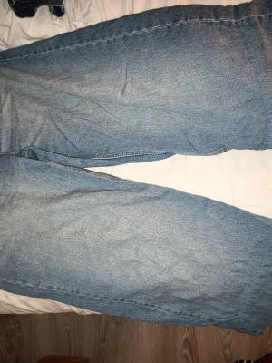 Baggy ljusblå jeans med raka ben - Baggy jeans i ljusblå denim med raka, vida ben och klassiska bakfickor. Jeansen har en avslappnad passform och är perfekta för en chill och trendig look. Materialet är klassisk denim i bomull.