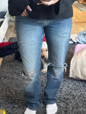 Blå raka jeans med slitningar - Säljer ett par blå jeans med raka ben och slitningar vid knäna. Jeansen har normal passform. Jag är 165