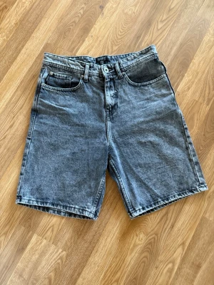 Grå jeanskjol med fickor - Säljer en grå jeanskjol i klassisk modell med fem fickor och knappgylf. Kjolen har en rak passform och är tillverkad i slitstark bomull. Perfekt till vardags för en avslappnad look.