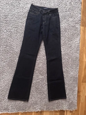 Mörkblå bootcut jeans  - Säljer ett par mörkblå bootcut jeans från med klassisk femficksdesign och kontrastsömmar. Jeansen har en hög midja och är tillverkade i stretchigt denim som sitter snyggt och bekvämt. Endast använda 1 gång och helt ny tvättade! Jag är 177cm lång och dom sitter perfekt längd på mig.