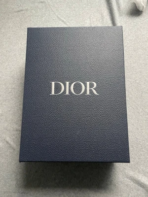 B30 - Exklusiv mörkblå handväska från Zara i lyxigt präglat läder. Väskan levereras i originalförpackning med tydlig Zara-logga på både box och väska. Perfekt accessoar för dig som vill sticka ut med stil och elegans.