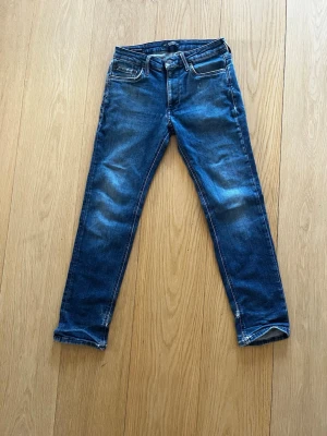 Blå jeans från Jack & Jones - Tja! Säljer nu dessa snygga blåa jeans från Jack & Jones i modellen Regular Clark. Jeansen har klassisk femficksdesign och raka ben. De är tillverkade i bomull med en skön passform som funkar till det mesta. De är använda och har några små slitningar, se bild 3, men det räknas förstås in i priset, ett pris som för övrigt kan diskuteras. Hör av dig vid minsta fundering!