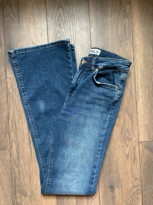 Blå bootcut jeans från ONLY - Snygga blå bootcut jeans från ONLY med klassisk femficksdesign och normalhög midja. Jeansen har en lätt tvättad look och är perfekta för en avslappnad stil. Tillverkade i denim med stretch för extra komfort.