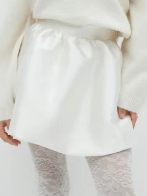 Vit kort satinkjol - Snygg vit kortkjol i satin med glansig finish. Kjolen har en enkel och clean look som passar perfekt till olika outfits. Lätt att matcha med både stickade tröjor och toppar för en trendig stil.