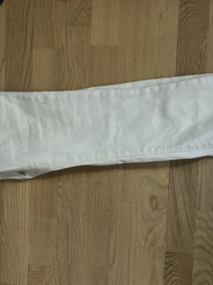 Vita bootcut jeans - Säljer ett par vita bootcut jeans med klassisk femficksdesign och normal midja. Jeansen har utsvängda ben och är perfekta för dig som gillar en retroinspirerad look. Materialet är denim i bomull. Passar till många olika stilar!
