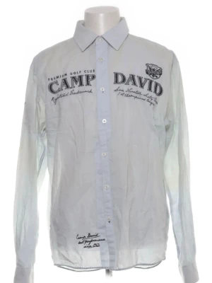 Vit skjorta från Camp David - Snygg vit skjorta från Camp David med tryck och broderade detaljer fram och bak. Klassisk krage, knäppning framtill och långa ärmar. Skjortan har en avslappnad passform och coola logotexter som ger en sportig vibe.