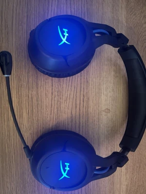 HyperX gaming headset med blå LED (TRÅDLÖST) - Snyggt gaming headset från HyperX med blå LED-belysning på öronkåporna och justerbar mikrofon. Svart design med mjuka öronkuddar och vadderad bygel för extra komfort. Perfekt för långa spelsessioner och tydlig kommunikation med laget.