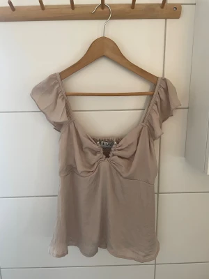 Fin top från Vero Moda - Fin top med detaljer från Aware Vero Moda.  Resår i ryggen. Silikonkant på axelbanden så de inte trillar ner. Fin ljus puderrosa färg. Sidenlikande tyg. Fodrad.  Slutsåld i butik. Märkt L, men skulle säga mer som en M