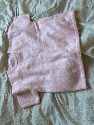 Två stickade t-shirts i pastell - Säljer två stickade t-shirts, en i ljusrosa och en i grått. Båda har korta ärmar, rund halsringning och är gjorda i ett mjukt, fluffigt material. Perfekta att styla med jeans eller kjol för en chill look. Den rosa kostar 50 och den grå 50 båda tillsammans kostar 80kr