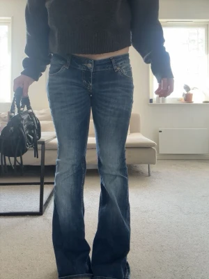 Blå bootcut jeans flared - Säljer ett par blå bootcut jeans från lager. Jeansen har låg midja och är tillverkade i denim med lätt stretch. Det är storlek S/short length och säljer för att de är lite för stors för mig.