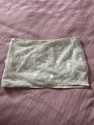 Vit paljettkjol med shorts  - Trendig vit kortkjol med glittriga paljetter som ger en snygg och festlig look. Har inbyggda shorts och även en dragkedja på sidan. Stora och små paljetter 