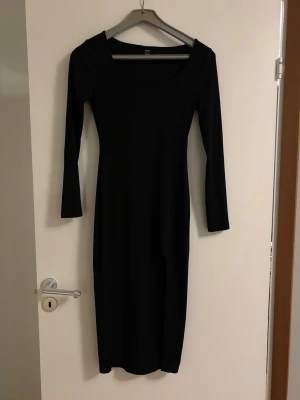 Svart långärmad klänning - En stilren svart långärmad klänning från Shein med rak passform, rundad halsringning och slits . Klänningen är enkel och tidlös, perfekt för dig som gillar minimalistisk stil. Materialet känns mjukt och följsamt mot kroppen. Skulle säga ett klänningen är Midi på mig som är 1,63🥰