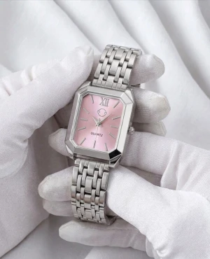 Silverfärgad klocka med rosa urtavla - Svensk märke. Cosmos Sweden. Stilren klocka med rektangulärt silverfärgat armband i metall och en rosa urtavla. Klockan har romerska siffror vid tolvan och klassiska indexmarkeringar. Länkat armband med smidig låsning. Perfekt accessoar för att lyfta din outfit.