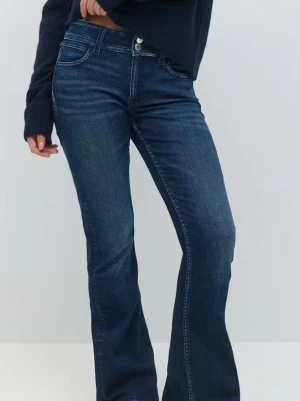 Blå bootcut jeans med knappar - Säljer ett par klassiska blå bootcut jeans med dubbla metallknappar och dragkedja. Jeansen har en snygg tvätt och kontrastsömmar. Materialet är denim i bomull och passformen är utsvängd nedtill för en retro vibe.