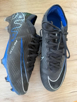 Fotbollsskor - Svarta och blå skor från Nike i fint skick, inte använda mycket då de var för små. 