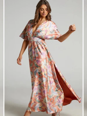 Blommig långklänning med v-ringning - Säljer en långklänning från Showpo, Australien med blommigt mönster i orange, rosa, vitt och grönt. Klänningen har djup v-ringning, korta vida ärmar och en slits i sidan. Tillverkad i ett glansigt, mjukt material som ger ett elegant fall. Aldrig använd, lappar kvar. 🌸