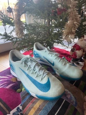 Nike ljusblå fotbollsskor - Nike skor som de inte är några större fel på förutom en lite svart fläck på dom. Annars ska dom var i bra skick!  Namn på sko: Nike air zoom mercurial vapor 16 Academy mad ambitation.   🚨 Inga låda   🟢 Inköpspris 1099kr