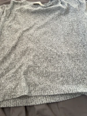 Ljusgrå stickad tröja - Mysig ljusgrå stickad tröja med rund hals och avslappnad passform. Tröjan har en enkel design utan synliga detaljer eller mönster och är perfekt för lager på lager. Materialet ser mjukt och bekvämt ut.