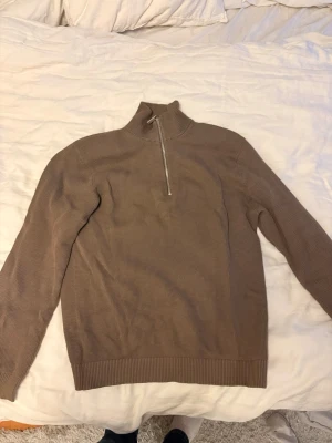 Selected home  stickad halvzip tröja - Snygg brun  stickad tröja med halvzip och hög krage. Tröjan har lång ärm och ribbade muddar vid ärmslut och nederkant. Perfekt för lager på lager och enkel att matcha med olika outfits.