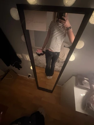 Randig t-shirt från KappAhl - Säljer en klassisk vit t-shirt med svarta horisontella ränder från  KappAhl