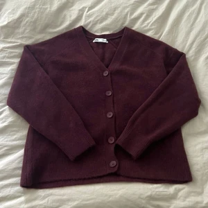 Slutsåld vinröd kofta från Zara - Mysig vinröd kofta från Zara med v-ringning och stora matchande knappar framtill.