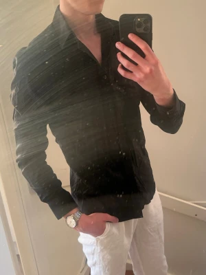 Svart skjorta från Bläck - (Lite dammig på en del ställen men går nog bort efter en tvätt!⚠️). Säljer en stilren svart skjorta med klassisk krage och knäppning framtill. Skjortan har lång ärm och en slim passform som sitter snyggt på kroppen. Perfekt för dig som gillar en clean och enkel look. 