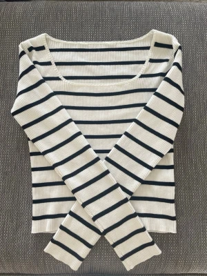 Randig ribbad långärmad topp - Snygg långärmad topp med svart och vit ribbad struktur och horisontella ränder. Toppen har en rundad halsringning och är tillverkad i ett stretchigt material som sitter skönt på kroppen. Perfekt för en enkel men stilren look.