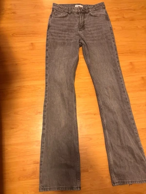Grå bootcut jeans med hög midja - Säljer ett par grå bootcut jeans med hög midja och klassisk femficksmodell. Jeansen har raka ben som blir vidare nedtill och är tillverkade i ett mjukt denimtyg. Perfekta för dig som gillar en retro och avslappnad stil. Jeansen är från ginatricot och original pris är 600kr men då dem är lite slitna nertill vid ankeln så säljs dem nu för 100 kr. Utöver den slitnaden längst ner är dem fortfarande i ytterst bra skick ☺️