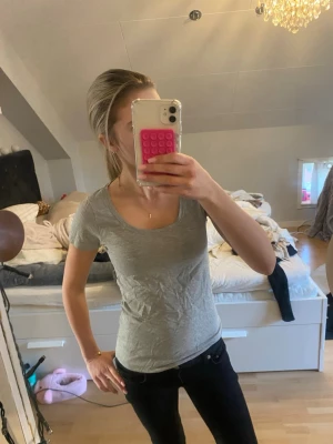 Ljusgrå basic t-shirt - En enkel ljusgrå t-shirt med rund halsringning och korta ärmar. Tillverkad i mjuk bomull och har en normal passform som sitter snyggt på kroppen. Perfekt att matcha med jeans eller kjol för en clean look.