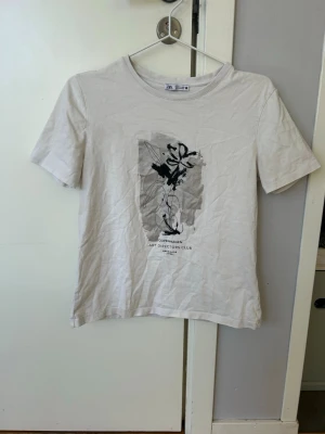 Vit t-shirt med tryck från Zara - Säljer en vit t-shirt med svart och grått abstrakt tryck på bröstet och texten 'Copenhagen Art Directors Club'💕💕Klassisk rund hals och korta ärmar💕💕I bra skick💕Jag säljer t-shiren för 50 kr💕💕Hör av er vid intresse💕💕