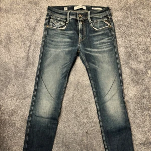Blå jeans från Replay - Snygga blå jeans från Replay i modellen Anbass med slim fit. De har en klassisk femficksdesign och en diskret tvätt för en modern look. Perfekta för en stilren vardagsoutfit. Priset går att diskutera vid snabb affär! Är även öppen för byten!!