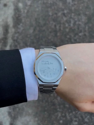 Stilren silverfärgad klocka - Snygg klocka i helsilver med länkarmband och rund urtavla. Urtavlan har en unik design med handskriven text och siffror. Perfekt accessoar för dig som gillar minimalistisk och modern stil.