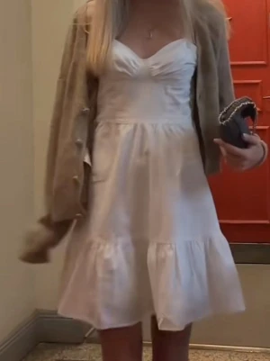 vit kort klänning med volang - perfekt för studenten eller skolavslutningen💘💘 älskar denna klänningen men tyvärr passar den inte mig längre, har endast användts 1 gång!!         söt vit kort klänning med volangkant och v-ringad byst. Klänningen har en feminin passform och tunna axelband, perfekt för varma dagar. Materialet ser ut att vara bomull eller linne för en luftig känsla.
