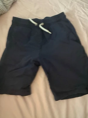 Mörkblå shorts med snörning Lindex - Snygga mörkblå shorts från Lindex med bekväm snörning i midjan och två sidofickor. Perfekta för varma dagar och har en avslappnad passform. Tillverkade i mjuk bomull för extra komfort.