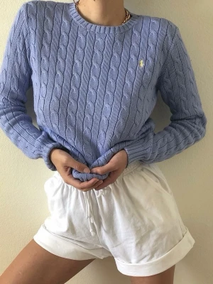 Polo Ralph Lauren tröja - Kabelstickad tröja i ljusblå färg från Polo Ralph Lauren. Superfint skick och storlek S.                           Observera att loggan är gul inte vit.