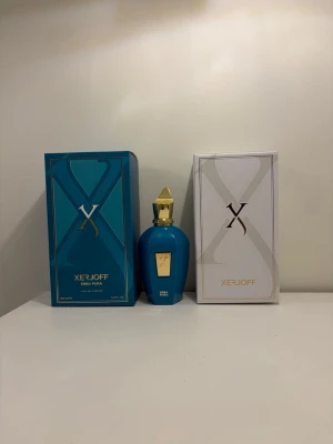 Xerjoff Erba Pura Eau de Parfum 100ml - Exklusiv parfym från Xerjoff, Erba Pura. Flaskan är blå med guldfärgad topp och detaljer, och har en elegant, rundad form. Levereras med både blå och vit originalkartong. Perfekt för dig som vill ha en lyxig och unik doft.