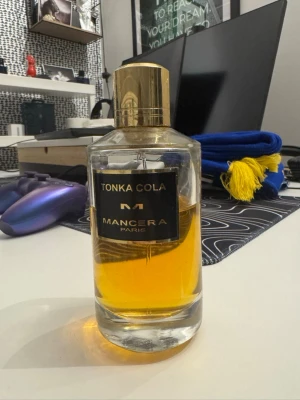 Mancera Tonka Cola parfym  - Unik parfym från Mancera, Tonka Cola, i en genomskinlig glasflaska med guldfärgat lock och etikett. Doften har en varm, bärnstensfärgad vätska och flaskan rymmer 120 ml. Snygg och modern design som sticker ut på parfymhyllan.