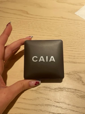CAIA Matte Bronzer Bombay - Snygg matt bronzer från CAIA i nyansen Bombay. Kommer i en stilren, fyrkantig kompakt dosa i mörkbrunt plastmaterial med silverfärgad logga. Perfekt för att skapa en solkysst look och definiera ansiktet med en naturlig finish.