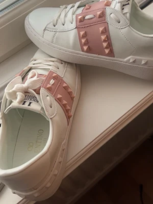 Valentino rockstud - Snygga vita sneakers från Valentino med rosa detaljer och ikoniska nitar i gummi på sidorna. Säljer pga fel storlek, använda fåtal gånger och är i jätte bra skick.