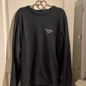 Svart sweatshirt från Calvin Klein Jeans - En svart sweatshirt från Calvin Klein Jeans med diskret logga broderad på bröstet. Perfekt för en clean och stilren look!✨