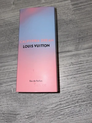 Louis Vuitton California Dream parfym - Louis Vuitton California Dream Eau de Parfum i en elegant glasflaska med svart lock. Doften kommer i en snygg förpackning med blå-rosa gradient och matchande vit cylinderask. Flaskan rymmer 100 ml och har en modern, lyxig känsla. Betalade 5300 kr för den men använd typ 2 gånger för att jag har för mycket parfym så behöver sälja ganska mycket för att jag behöver pengarna nu , pris kan diskuteras 